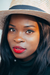 Beautiful young black african girl in a hat with a happy smile on the street in the rays of the setting autumn sun. close-up. Fashion colors