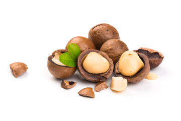 Macadamia nut with pieces and green leaves isolated on a white background