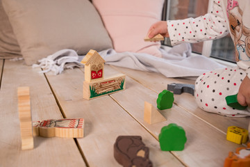 Tiny colorful wooden toy shapes and building blocks on hardwood floor.Girl play with a wooden set in their children's room on the floor. colorful blocks on the floor.cute wooden toy animal , tiny toys