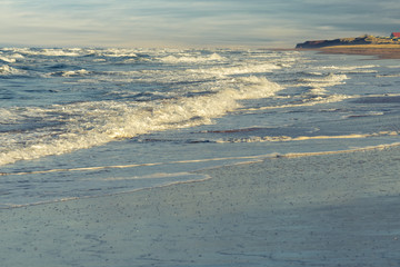 Surf rolls in on a sandy beach on the north shore of Prince Edward Island, Canada.
