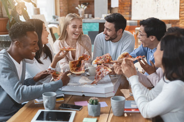 Happy people eating pizza at office during lunch time