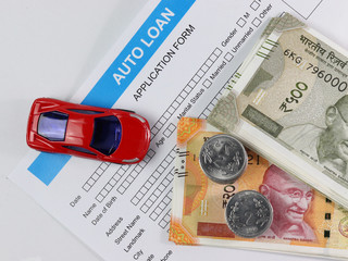 Car loan. Auto finance. Red car with indian currency notes, coins and application paper. 