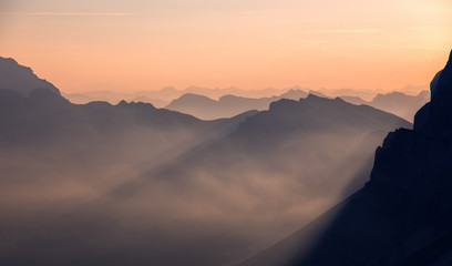 Fantastic misty morning in the dolomites Alps. landscape with colorful misty silhouettes of mountains  with rays . Nature background, scenery. Awesome alpine highlands during sunset. Shot from Seceda