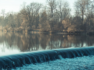 Water flowing over a weir during sunset in the winter, Augsburg, Germany
