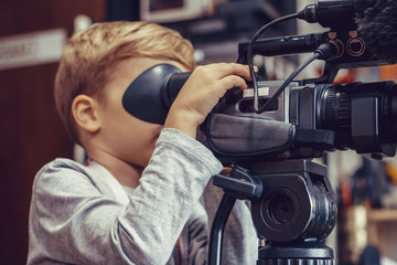 Little boy shooting video with camera in a studio.