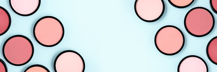 Pink blush and compact powder on a pastel blue background. Banner. Place for text, design. Top...