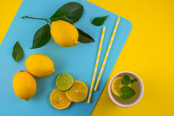 Zero waste concept. Yellow and blue paper environmentally friendly straws and paper cup with lemons on blue paper background with copy space. Flat lay, top view.