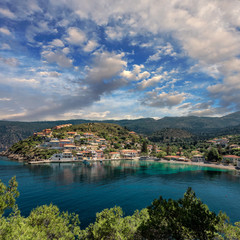Fototapeta na wymiar Breathtaking rocky coastline with colorful houses of Assos village, Kefalonia Island. Greece, impressively beautiful seascape with picturesque sky during sunset.