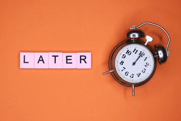 Later word and alarm clock on an orange background.