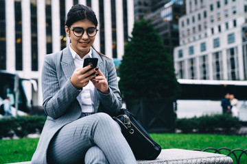 Obraz premium Woman office worker booking online via mobile phone plane ticket for business trip overseas happy with received discount, successful managing director typing email message on cell smartphone