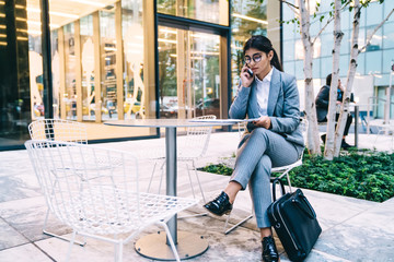 Young woman in office suit with paperwork talking on phone