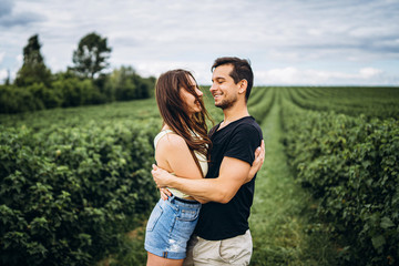 A tender loving couple walking in a field of currant. Man whirls woman in her arms. Love story