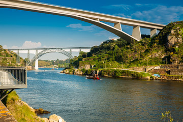 View of a vintage traditional boat sailing on the Douro River and some of the bridges that cross...