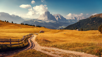 Splendid autumn landscape in Dolomites Alps. Beautiful countryside landscape with tradition huts, agriculture and dirt road hiking trails just outside Albions, Val Gardena, Italy