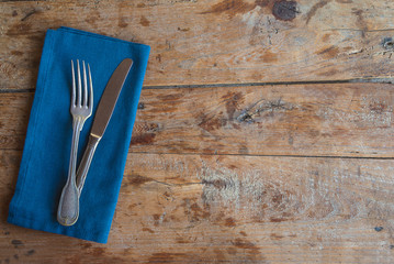 Table setting in vintage style. Antique knife and fork on linen napkin on old wooden background. Space for text, flat lay