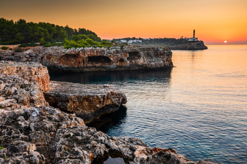 Sunrise with rocks and Porto colom lighthouse
