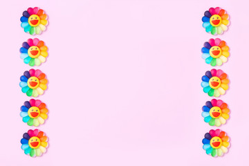 Pink background with flowers. Toy flowers with petals of various colors. Greeting card.