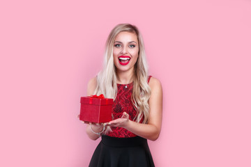 beautiful young blond woman with a red gift box on pink background