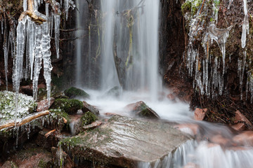 winterlicher kleiner Wasserfall mit Eiszapfen