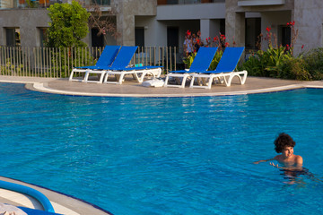 Happy boy in swimming pool in tropical resort