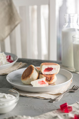 Cheesecakes from cottage cheese with raspberry marmalade on a plate with sour cream and a glass of milk.