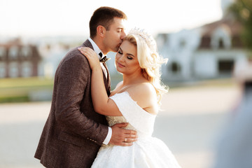 Naklejka premium The bride and groom walk together in the park. Charming bride in a white dress, the groom is dressed in a dark elegant suit