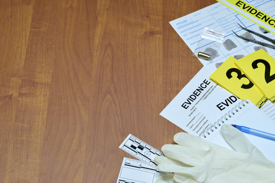 Paperwork during crime scene investigation process in csi laboratory. Evidence labels with fingerprint applicant and rubber gloves on vooden table