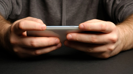 Close up of a man using mobile smart phone. Smartphone in male hands. Closeup of young man Playing videogames On Mobile phone