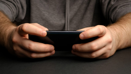 Close up of a man using mobile smart phone. Smartphone in male hands. Closeup of young man Playing videogames On Mobile phone