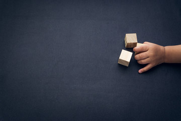 Wooden cube alphabet closeup and children hands on black background. Selective focus and education concept