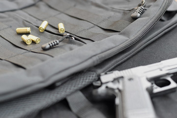 9mm bullets and pistol lie on a black tactical backpack