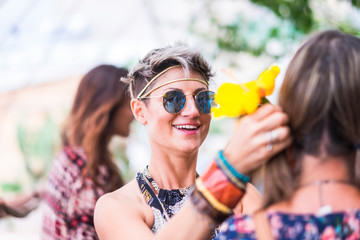 Cheerful coloured hippy style free and smiling young blonde alernative woman with friends together have fun outdoor - traditional festival or different lifestyle concept for happy people