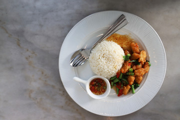 Close up Crispy Chicken with Basil In a white circular dish Placed on a marble table By taking from above