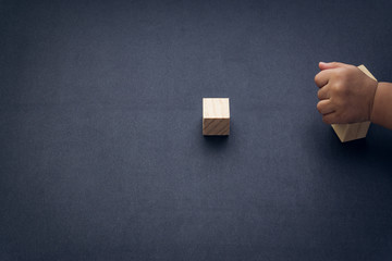 Wooden cube alphabet closeup and children hands on black background. Selective focus and education concept