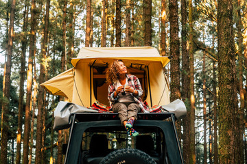 Travel and wanderlust lifestyle concept with happy lonely adult woman sit down on the roof tent car...