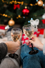 couple toasting with champagne, glasses with champagne on Christmas tree background