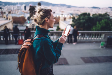 Joyful female tourist with smartphone exploring city - obrazy, fototapety, plakaty