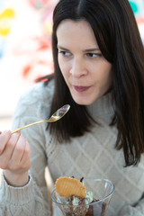 Beautiful brunette woman eating an ice cream from a cup. Selective focus