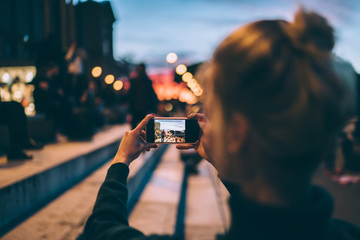 Back view of female generation photographing city urban setting during journey getaway connected to...