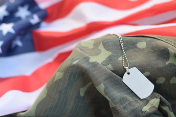 Silvery military beads with dog tag on United States fabric flag and camouflage uniform
