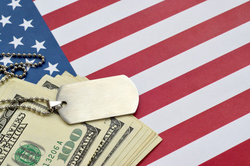 Army identification medallions and dollar bills on United states flag. Military pension, salary in...