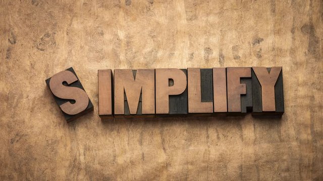 Simplify word, minimalism, essentialism and simple living concept - stop motion animation with vintage letterpress wood type block against handmade bark paper.