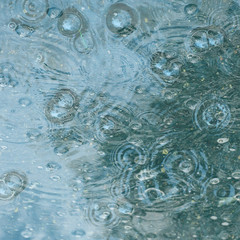 blue background puddle of rain / raindrops, circles on a puddle, bubbles in the water, the weather is autumn