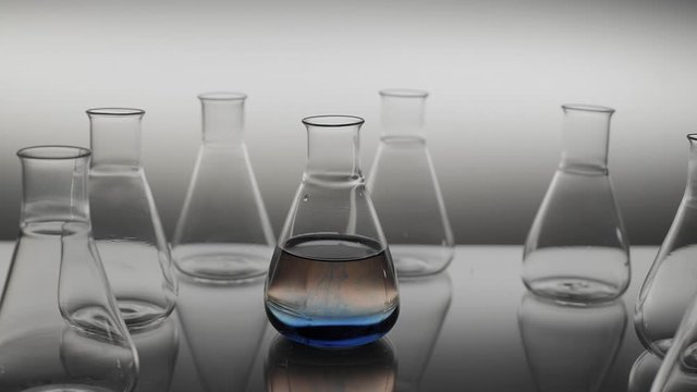 The blue liquid spills over water in erlenmeyer flask.