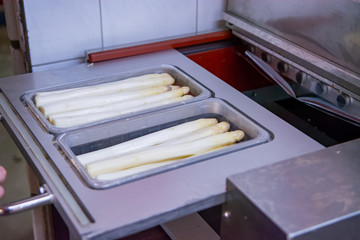 Industrial processing of white asparagus vegetable on agricultural farm in Netherlands, washing, peeling, sorting and packing for delivery