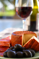 Tastes of Spain, jamon iberian, black olives, manchego cheese with red paprika and glass with red rioja wine