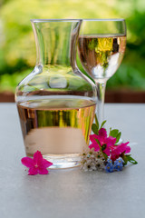 French rose wine served in garden in glass and carafe with colorful spring flowers