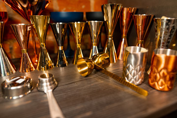 Professional bartender equipment as different metal color jiggers and glasses