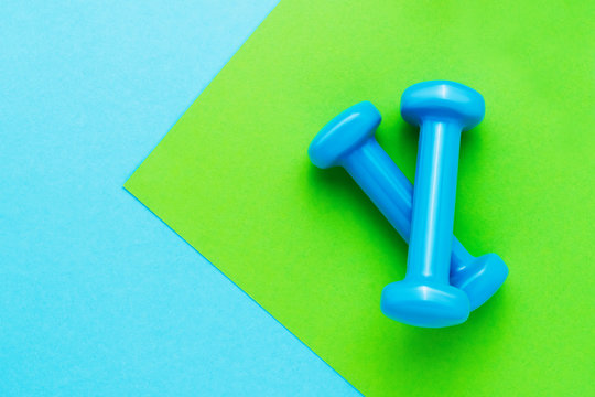 Blue dumbbells lie on green-blue background. The concept of healthy lifestyle. Copy space, top view