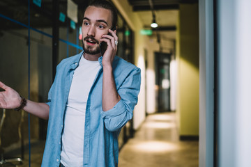 Surprised man talking on mobile phone in building